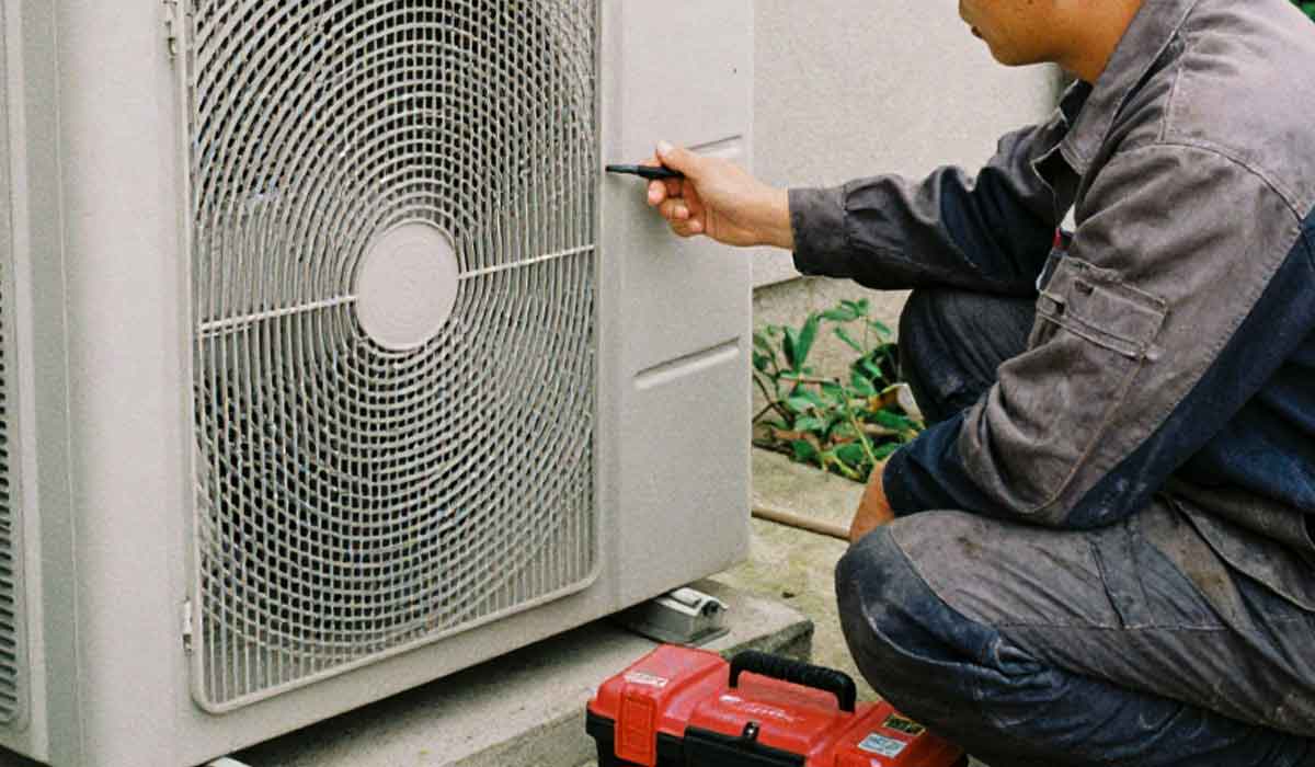 HVAC technician servicing an outdoor AC condenser unit during repair