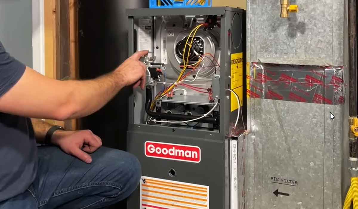 This image shows a technician inspecting the internal components of an open Goodman furnace connected to residential ductwork. It is ideal for content about furnace repair, heating system inspections, HVAC maintenance, and home comfort service.