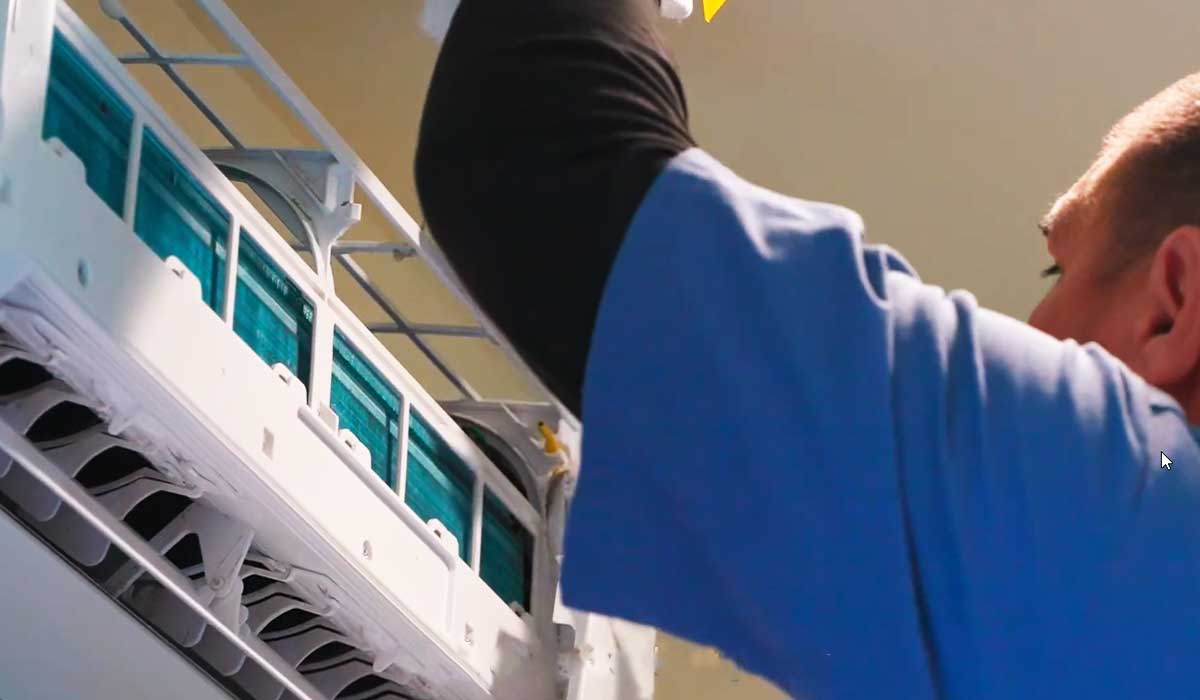 Technician cleaning a wall-mounted mini-split AC indoor unit during maintenance