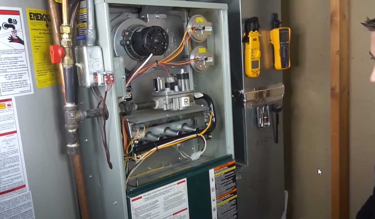 Open gas furnace cabinet with visible components and diagnostic tools during HVAC inspection