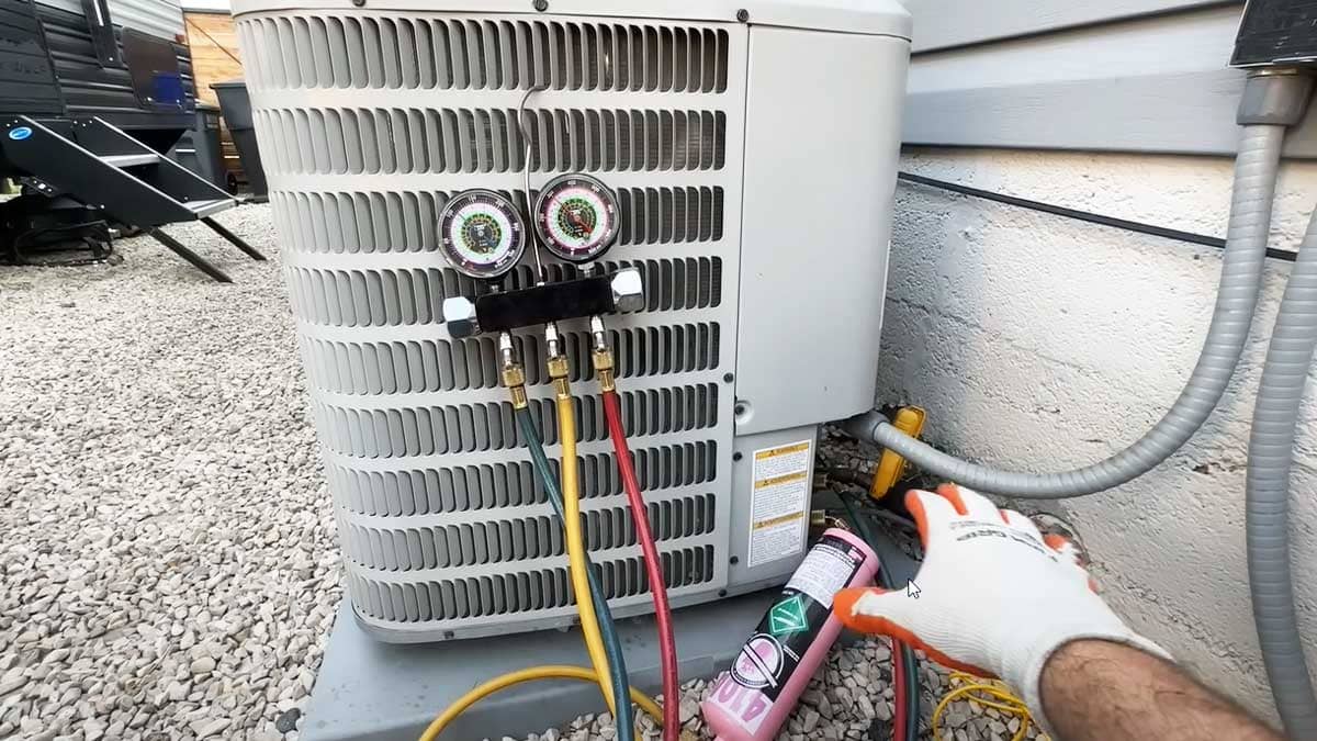 A technician’s gloved hand reaches for a refrigerant canister beside an AC unit with pressure gauges, showing detailed HVAC services in North Carolina.
