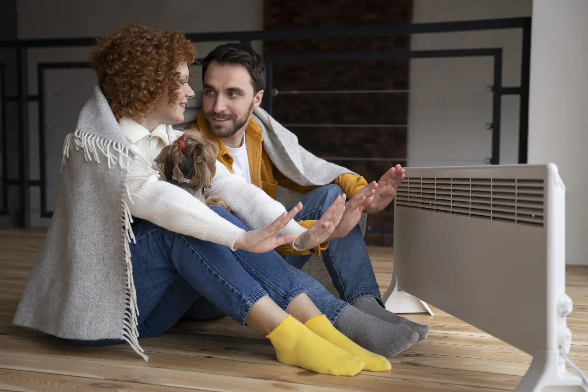A family of three warms their hands by an electric heater on the floor of a bright modern room, showcasing reliable HVAC services in North Carolina.
