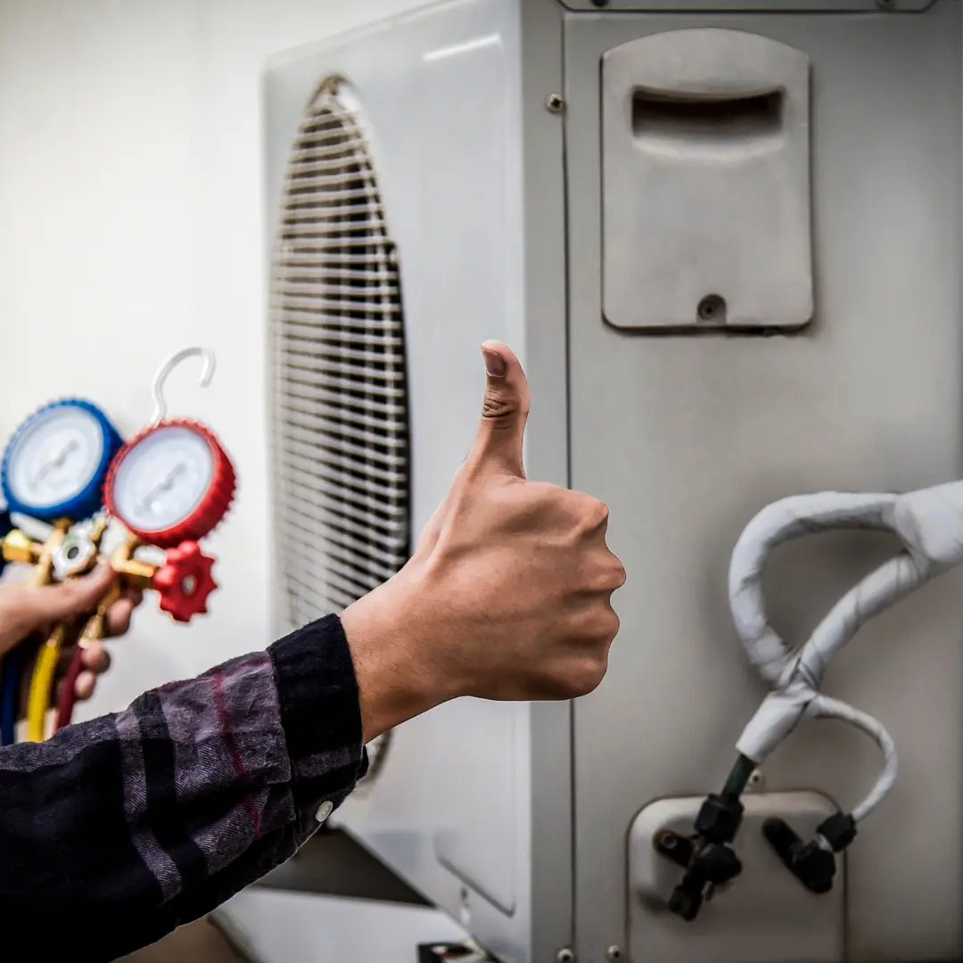 A man holds a thermometer while pointing at an HVAC unit, indicating a temperature check or maintenance task.
